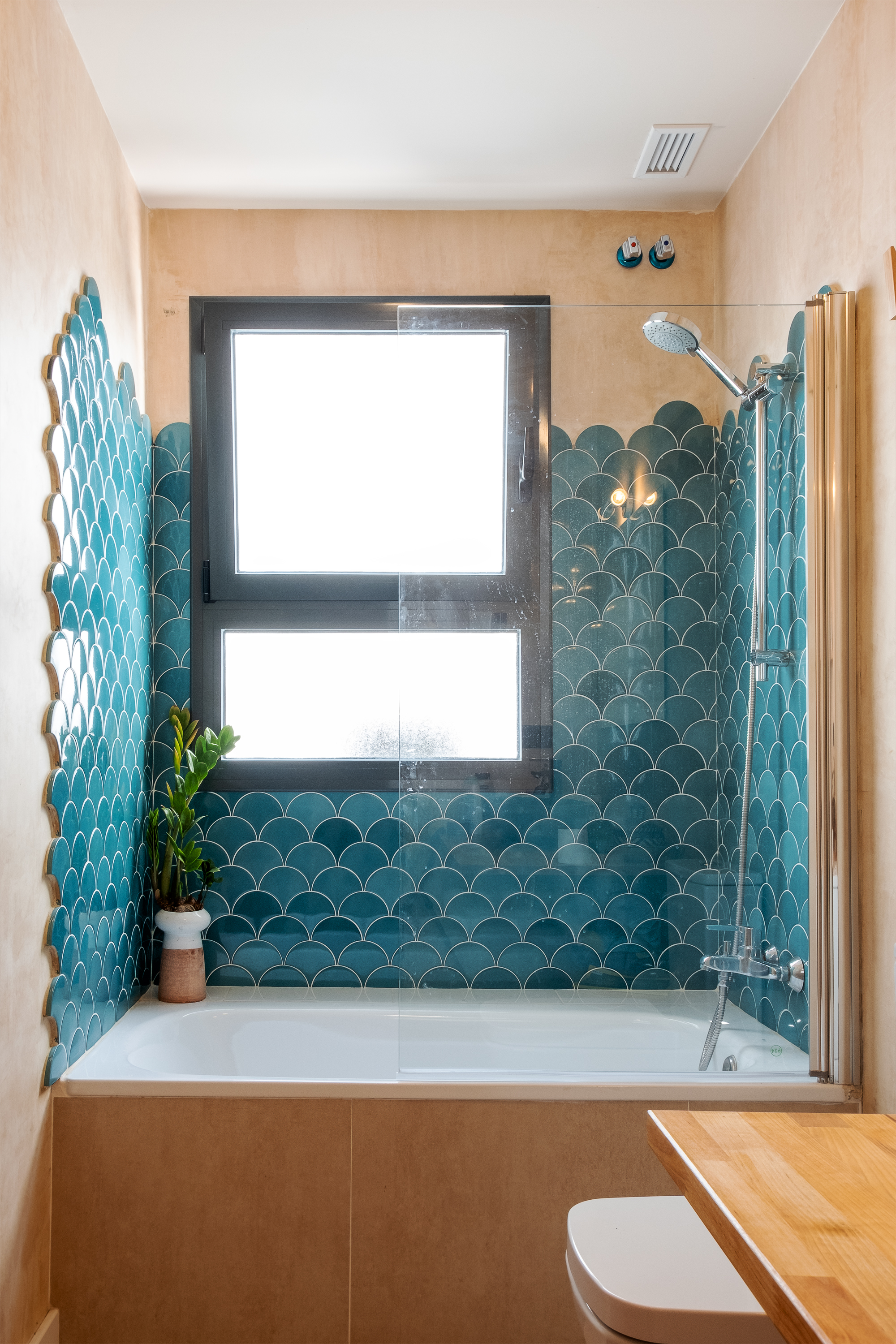 Baño de Casa Gomo con cerámica azul, madera natural y lavabo de aspecto pétreo, diseñado en relación con la naturaleza.