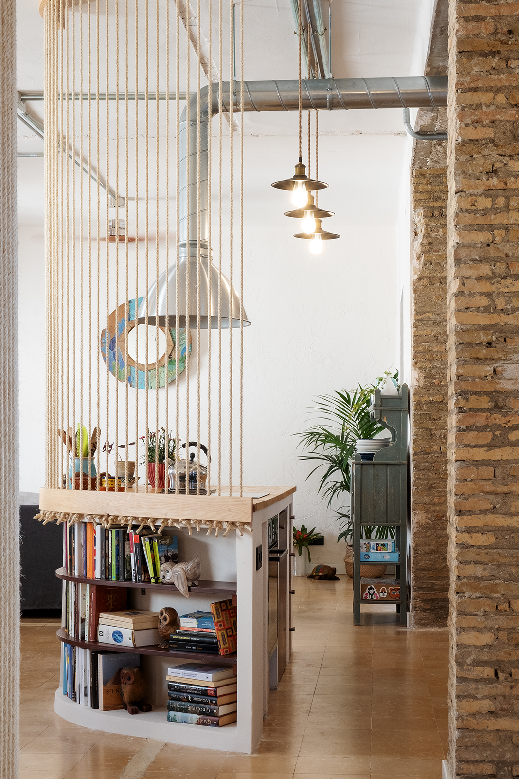 Partición ligera de cuerdas de cáñamo que separa la cocina del comedor sin perder la conexión visual en Casa Gomo.