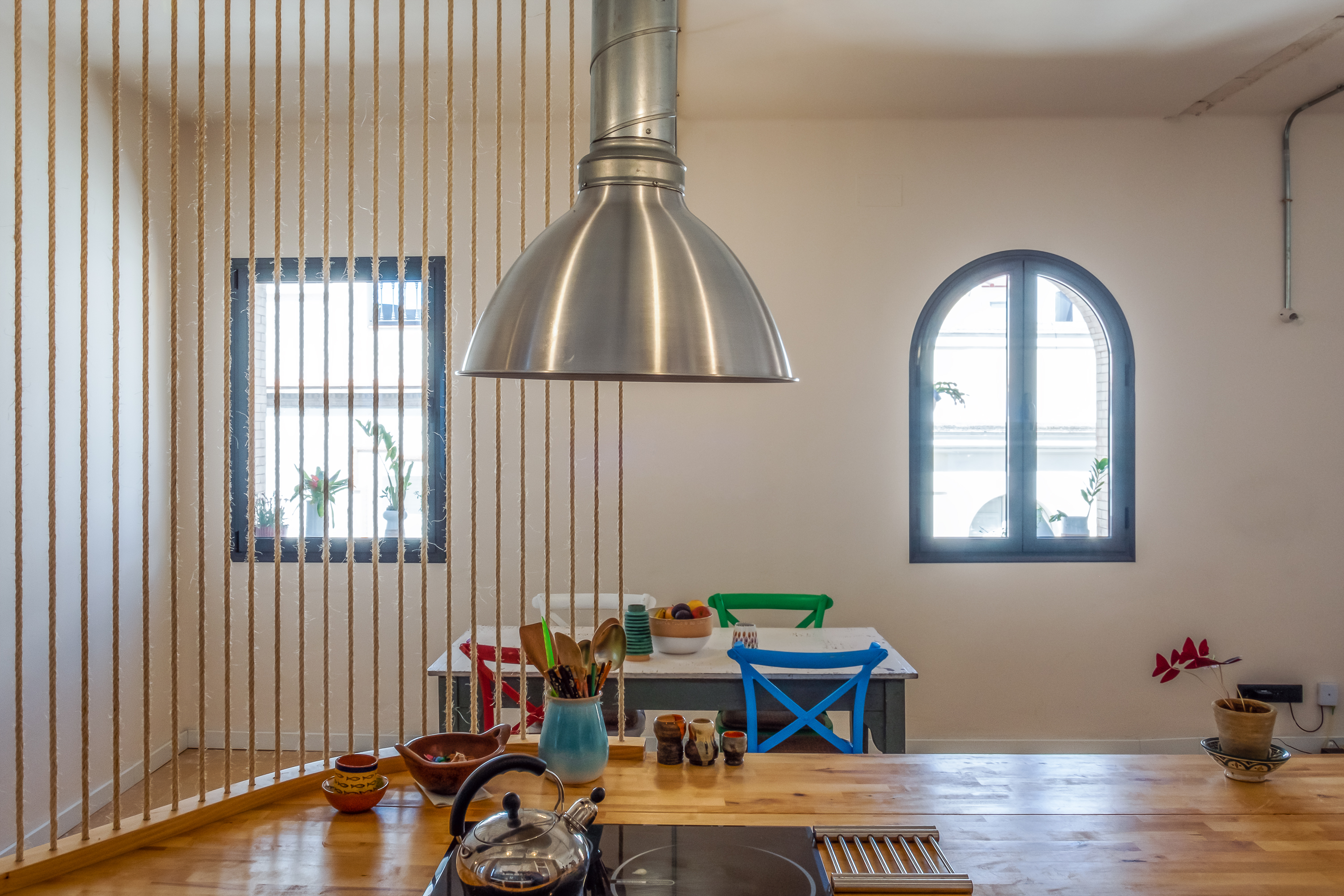 Cocina abierta de Casa Gomo con isla de obra, almacenamiento y biblioteca conectada con el espacio de día.