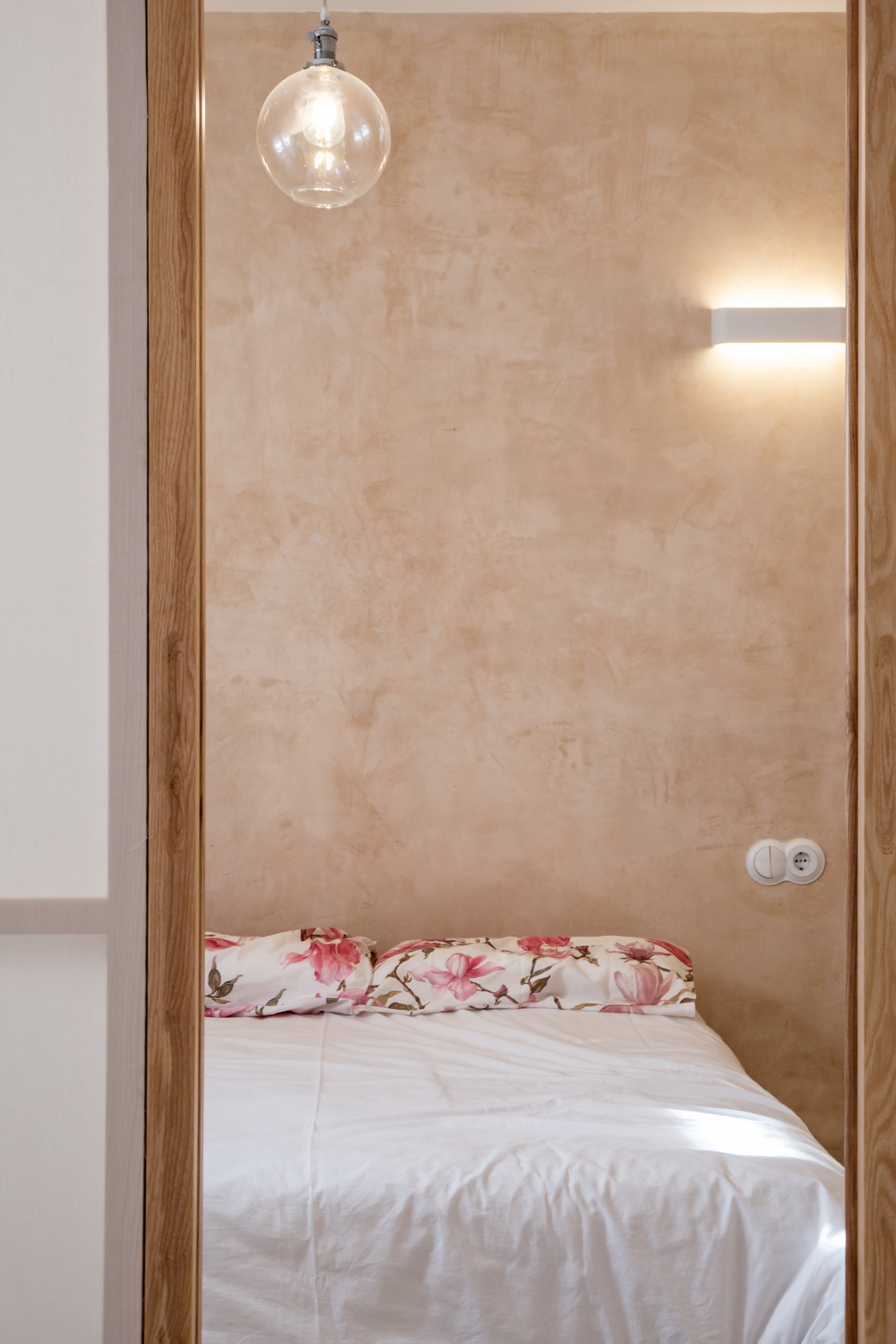 Vista del dormitorio principal de Casa Atelier, concebido como un espacio sereno donde la continuidad de los materiales favorece el descanso.