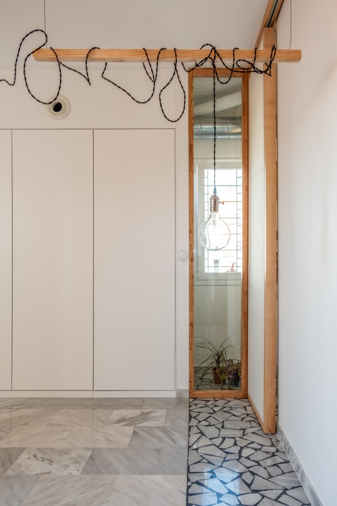 Estructura de madera inspirada en un bastidor de pintura con espejo integrado y paneles correderos diseñados para Casa Atelier.