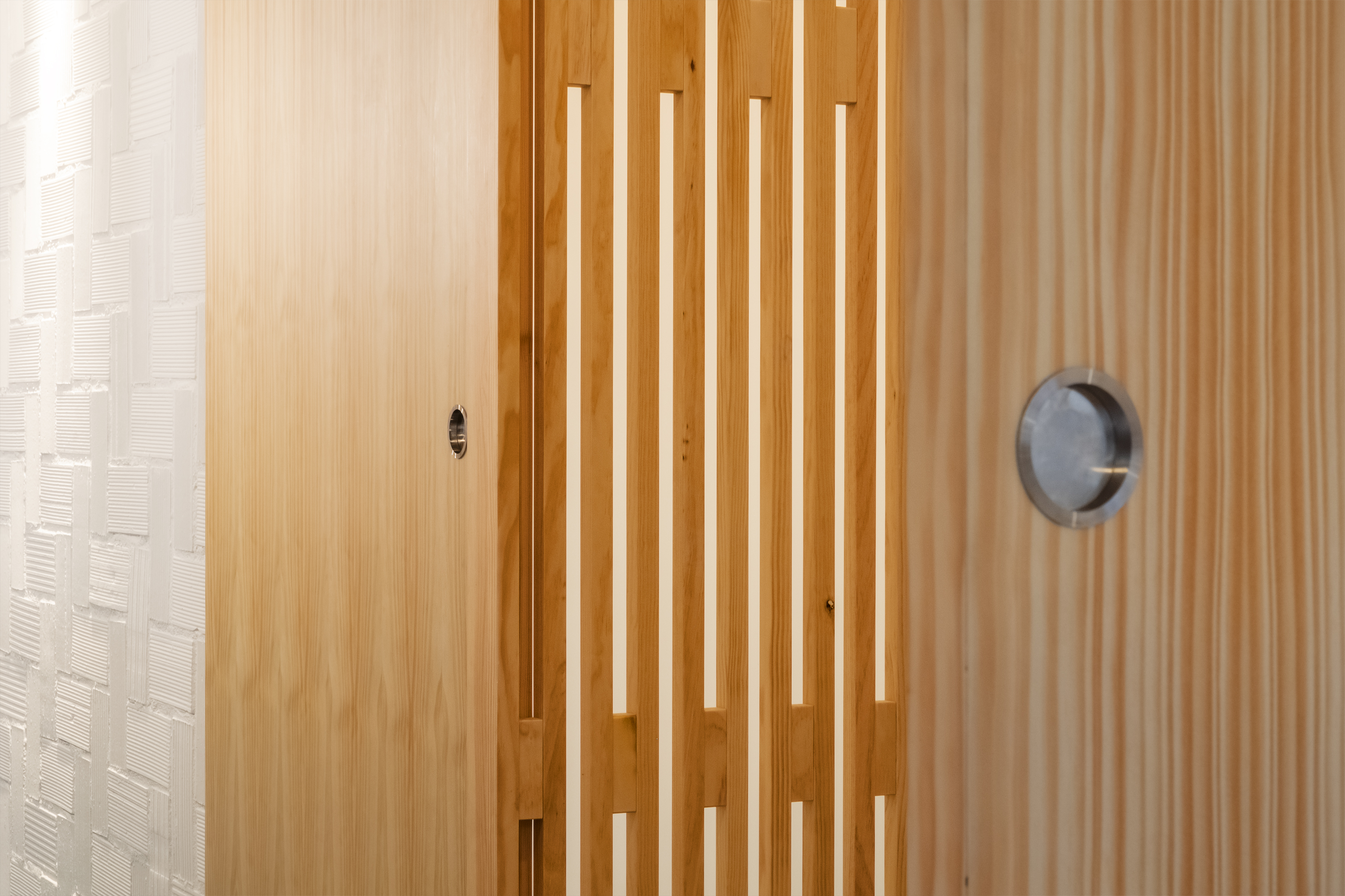 Celosía de madera que permite ver el salón de la vivienda Homeping desde el acceso