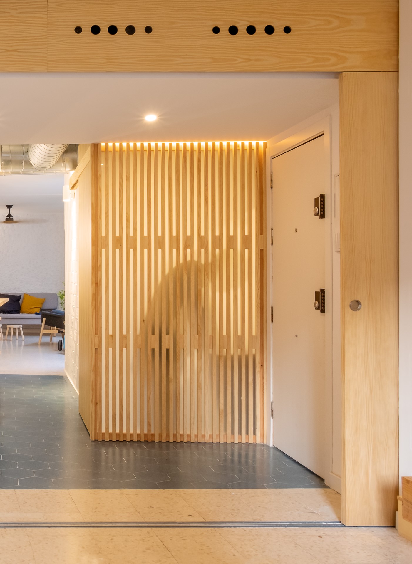 Celosía de madera de pino que separa visualmente el acceso y el interior de Homeping